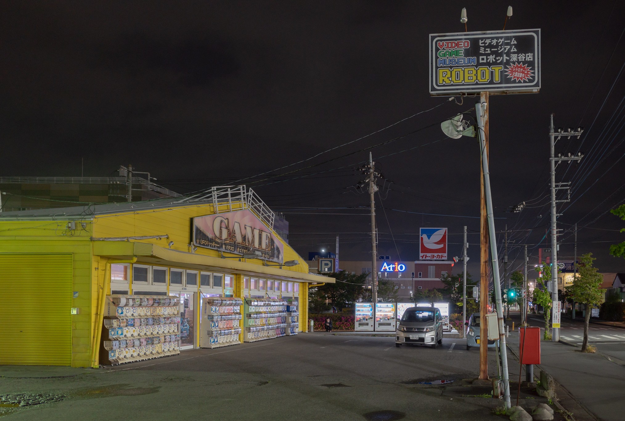 Ein Foto zeigt ein Äußeres einer japanischen Arkade mit einem Parkplatz und einem veralteten Schild mit der Aufschrift „Videospiel -Museumsroboter“.