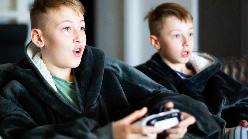 Zwei Jungen spielen zusammen ein PlayStation 5 -Spiel.